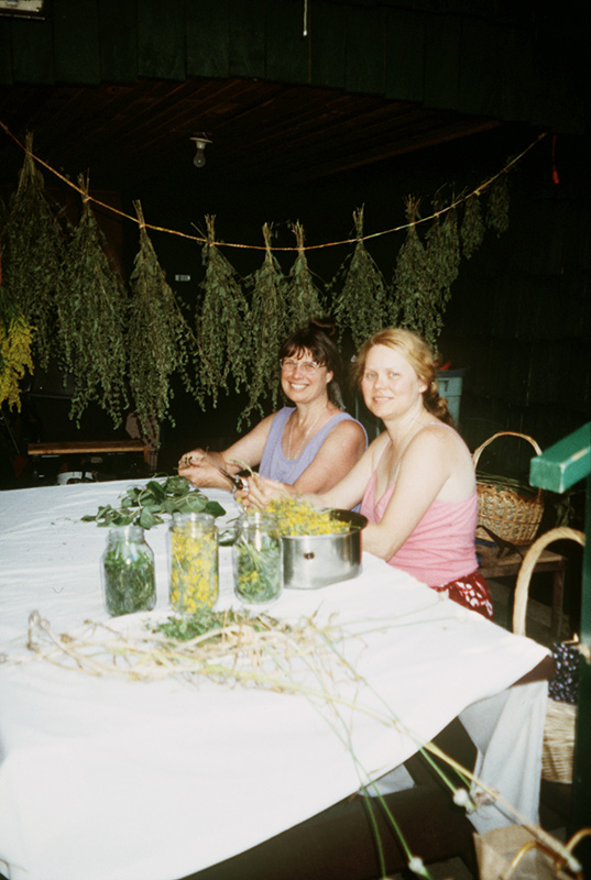 Two women at a table full of herbs