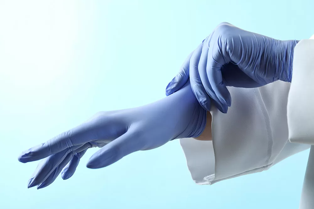 Doctor putting on blue medical gloves